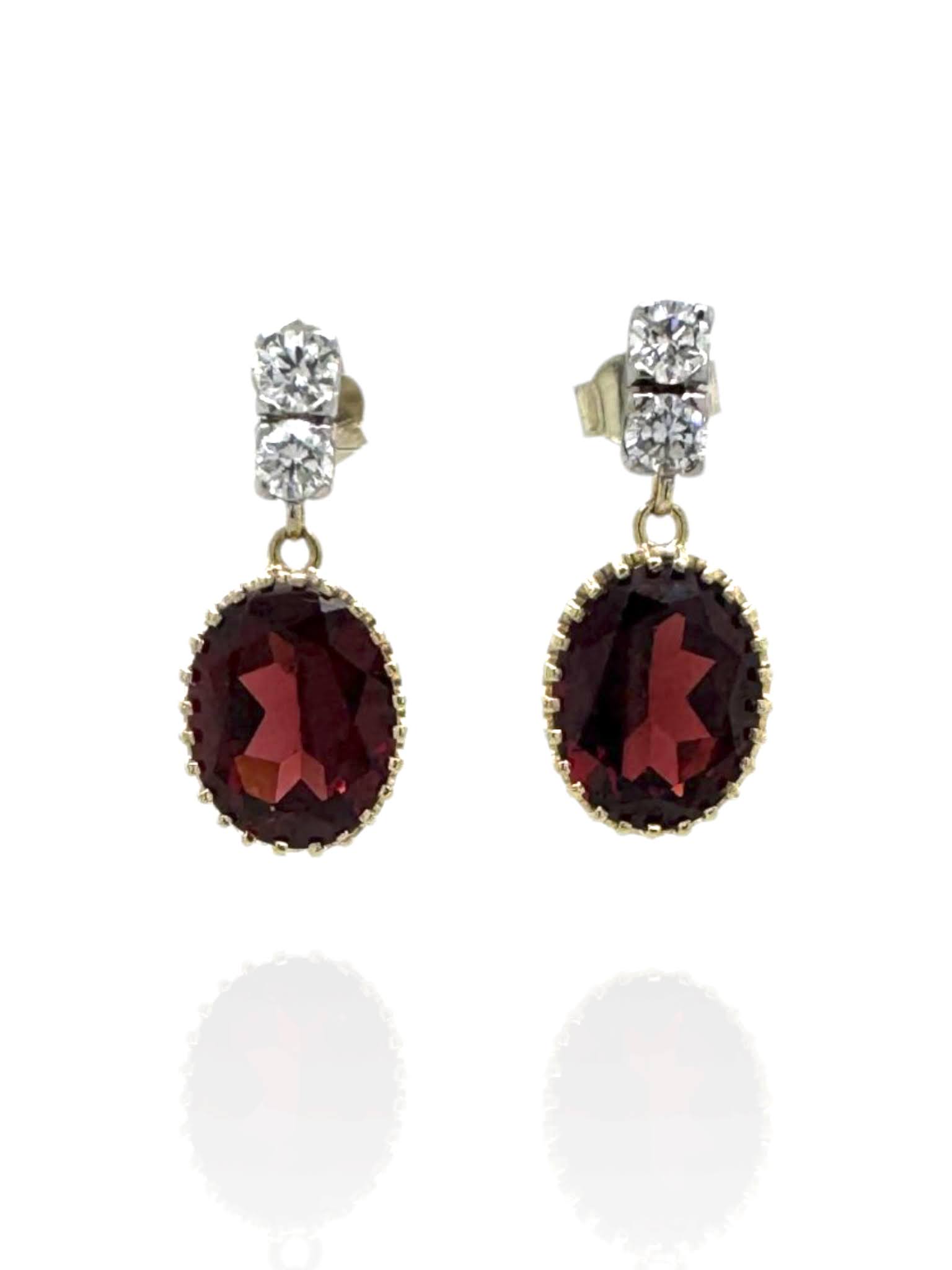 Gouden oorhangers met twee diamanten in witgoud en een granaat in een geelgouden kranszetting.